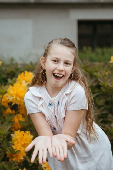 Girl striking a pose near some yellow flowers in her sweater dress