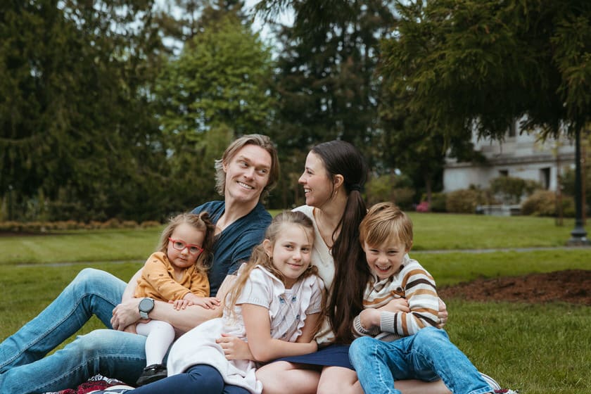 Family sitting on the grass laughing together in their spring outfits