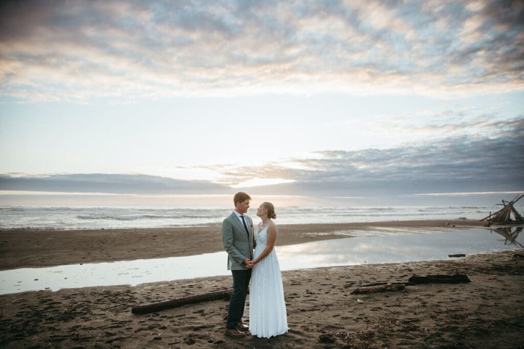 A couple standing on the beach on their wedding day after their backyard wedding