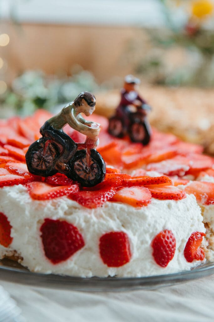 A biking figurine on a white strawberry cake