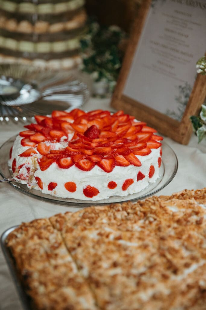 A white cake with bright red strawberry slices on top