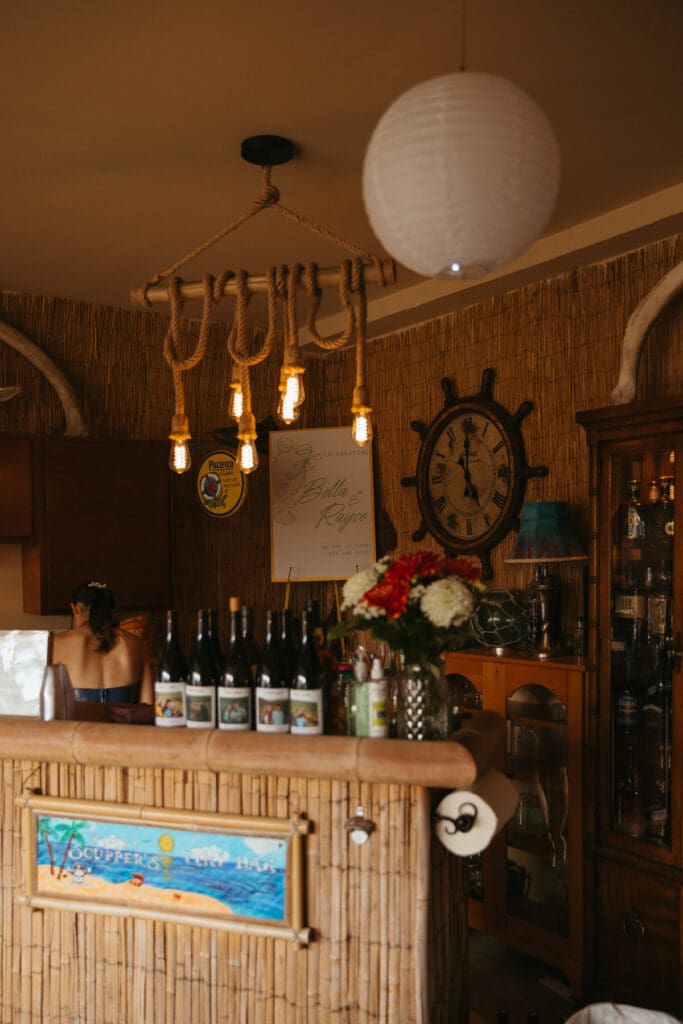 A tiki bar with decorative lighting at a backyard wedding