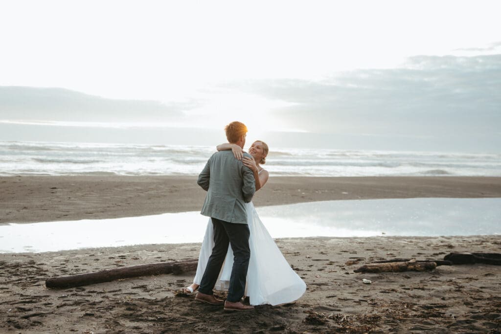 Bride and groom dancing on the beach during sunset