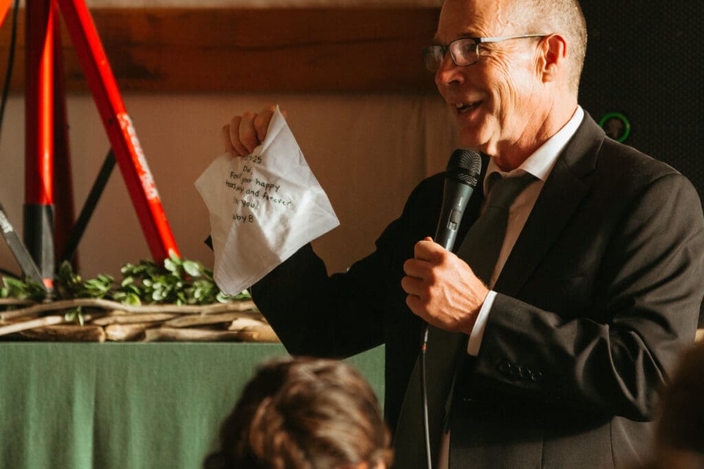 A father of the bride giving a speech and holding up an embroidered handkerchief 