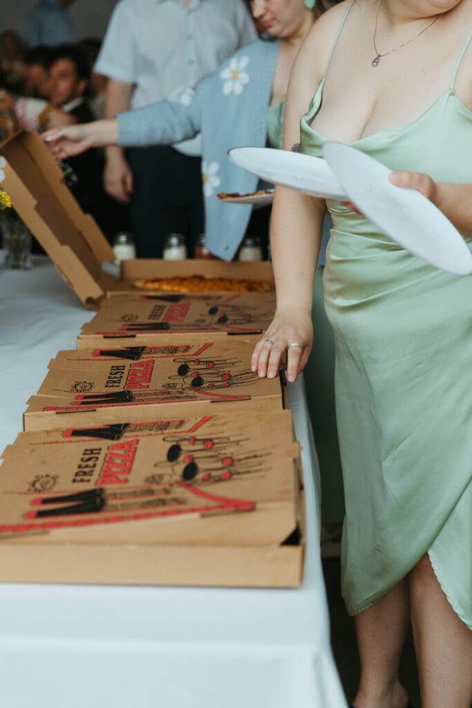 Pizza boxes in a line on a table at a backyard wedding