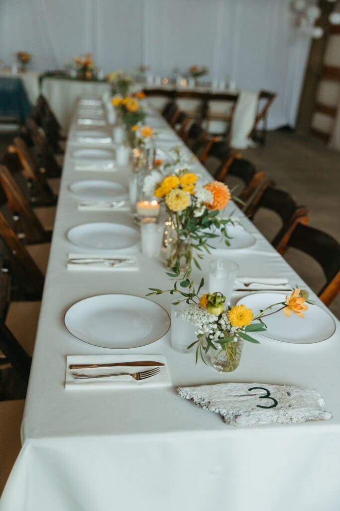 White table setting with yellow and orange flowers